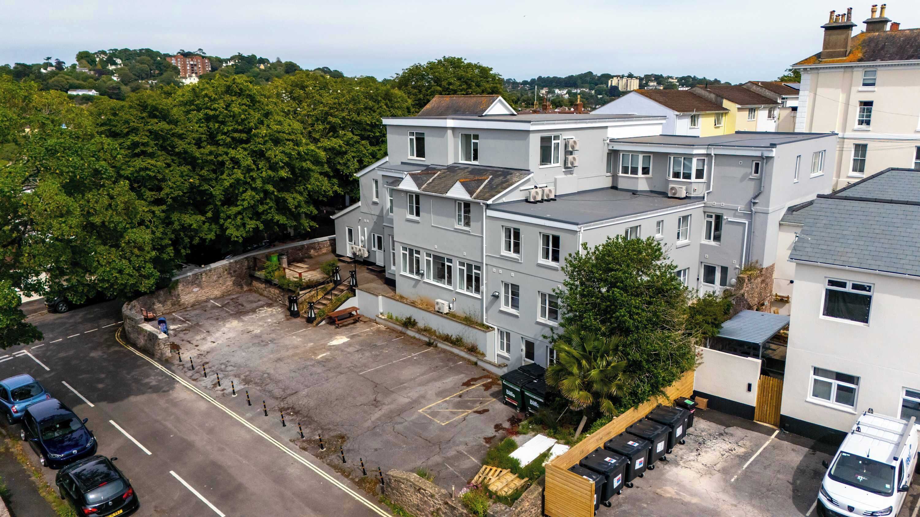 A multi-story residential building with a parking area in front.