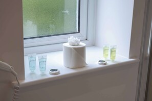 A bathroom window sill with toiletries including a tissue roll, two bottles of shampoo, and a soap dish. - The Maycliffe - Studio near Torquay Harbour (Torquay)