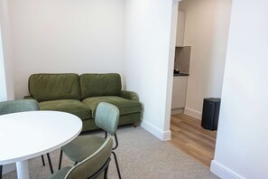 A room with a green sofa, a white round table, and a black speaker. - The Maycliffe - Spacious Studio near Harbour (Torquay)
