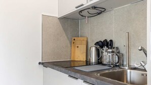 Uma cozinha moderna com uma pia de aço inoxidável, uma tábua de corte de madeira e diversos eletrodomésticos.