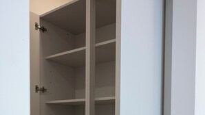 Um armário branco com várias prateleiras e uma porta com puxador redondo.