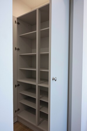 A white closet with multiple shelves and a door with a round handle. - The Maycliffe - Spacious Studio near Harbour (Torquay)