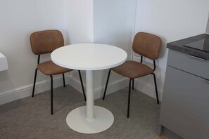 A small, round table with two chairs, a white wall, and a grey cabinet. - The Maycliffe - Modern Studio nr Harbour (Torquay)