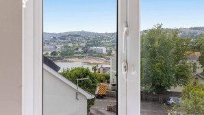 Blick durch ein Fenster auf ein Wohngebiet mit einem Fluss, Gebäuden und einem Lastwagen auf der Straße.