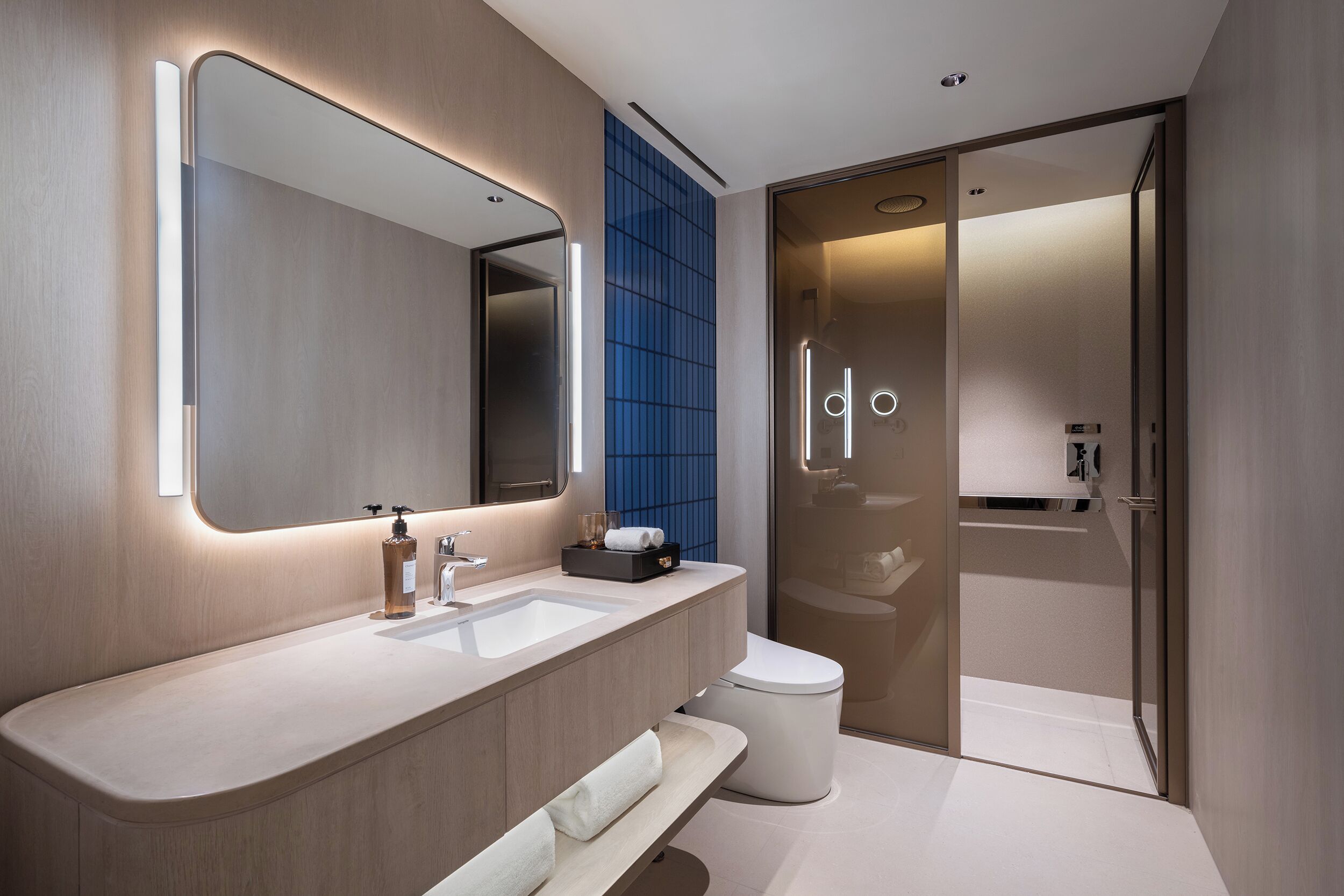 Een moderne badkamer met een grote spiegel, een wastafel, toilet en douche.