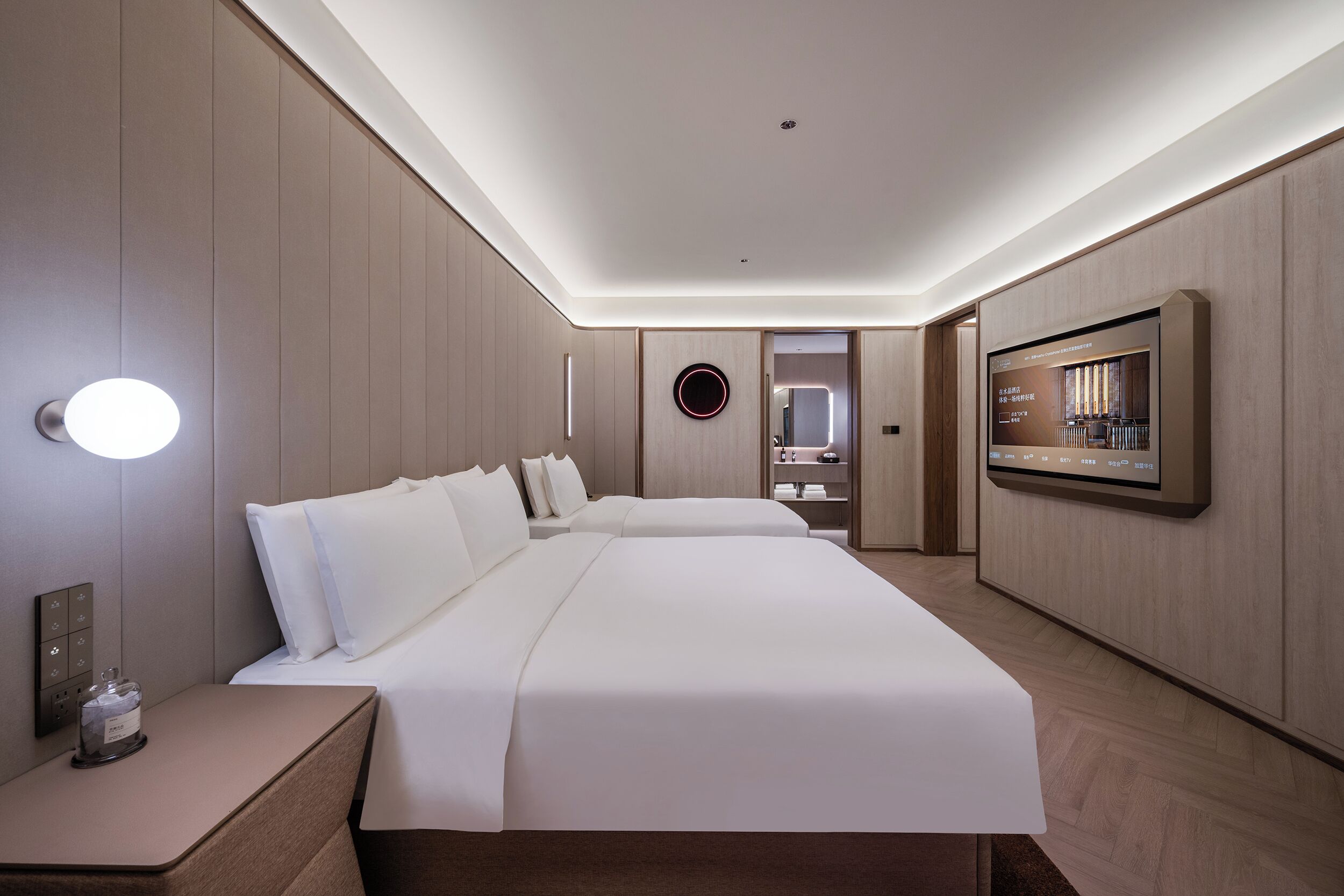 Ein Hotelzimmer mit einem großen Bett, Nachttischen, einem Fernseher und einem wandmontierten Spiegel.