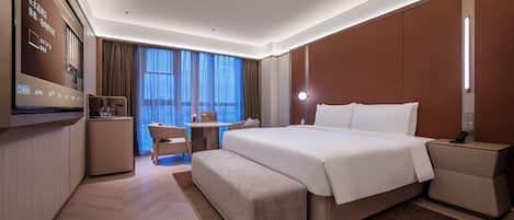 Una habitación de hotel con una cama grande, un escritorio, una silla y un televisor.