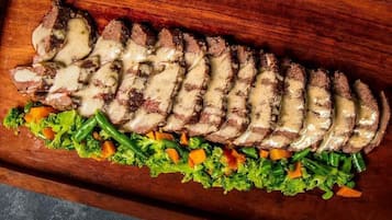 A wooden board with sliced meat and a vegetable salad.
