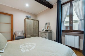 A bedroom with a bed, a wardrobe, a dresser, a chair, and a window with curtains.