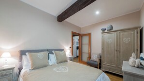 Een slaapkamer met een groot bed, een kledingkast, een nachtkastje en een dressoir.
