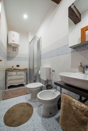A bathroom with a toilet, bidet, sink, and a shower area. - Vrbo Property (Torino)
