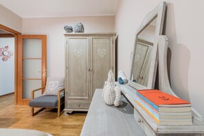 Une pièce comprenant une armoire en bois, une chaise, une table avec des livres et un miroir.