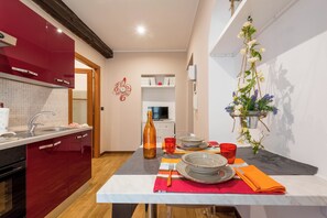 Une cuisine moderne avec des meubles rouges, un pare-feu en carreaux et un coin repas agrémenté d’assiettes, de verres et d’une bouteille.