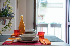A dining table set with plates, bowls, and glasses, with a bottle and a flower arrangement on the side. - Vrbo Property (Torino)