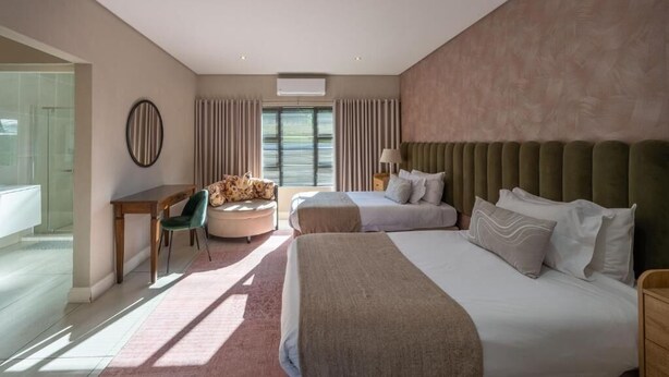 A hotel room with two beds, a desk with a chair, a round mirror, and a window with curtains. - Khaya Elihle Guest House (Sabi River Eco Estate)