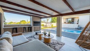 A modern outdoor living space with a pool, seating area, and a bar. - Khaya Elihle Guest House (Sabi River Eco Estate)