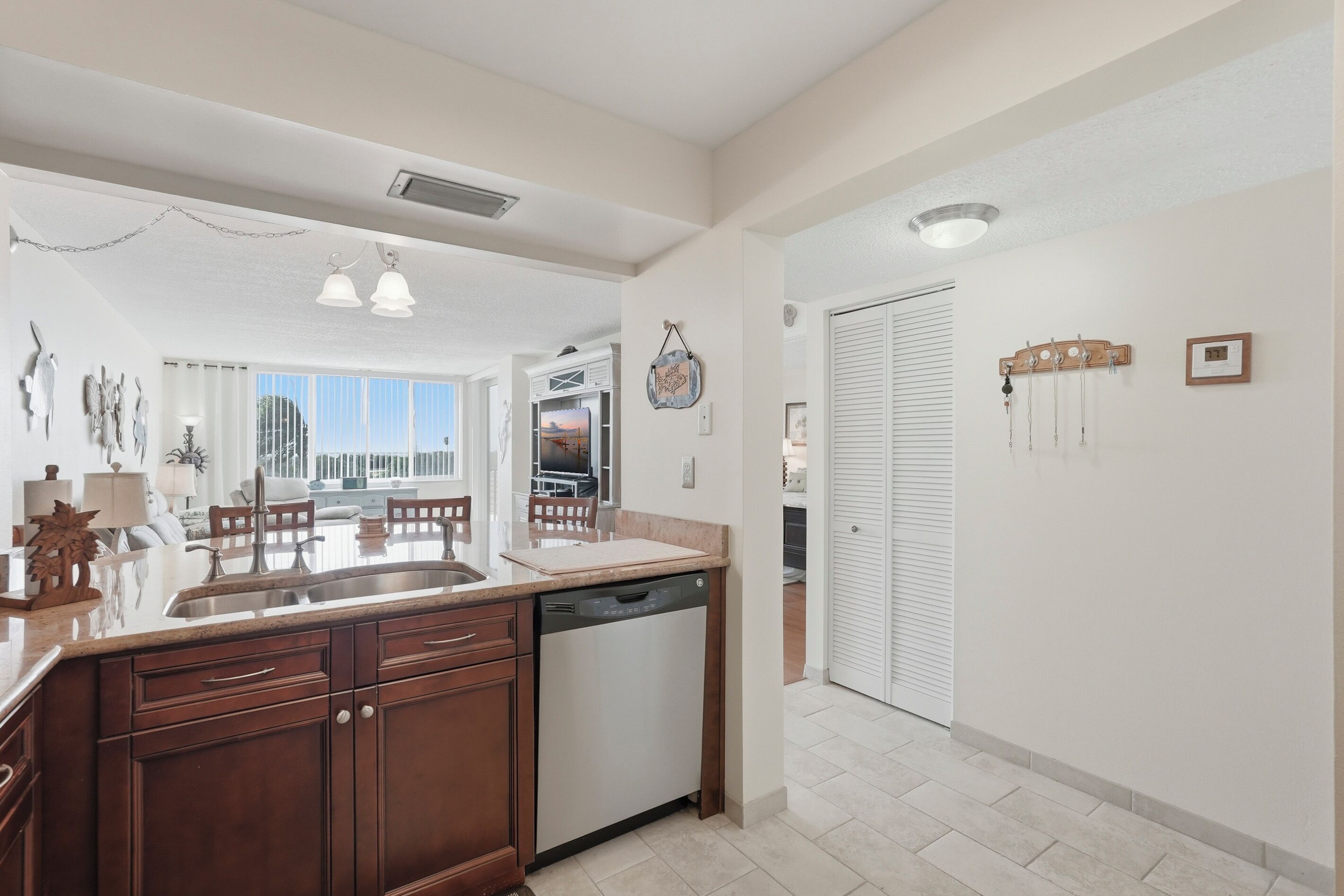 A modern kitchen with a dishwasher, wooden cabinets, and a dining area with a view.