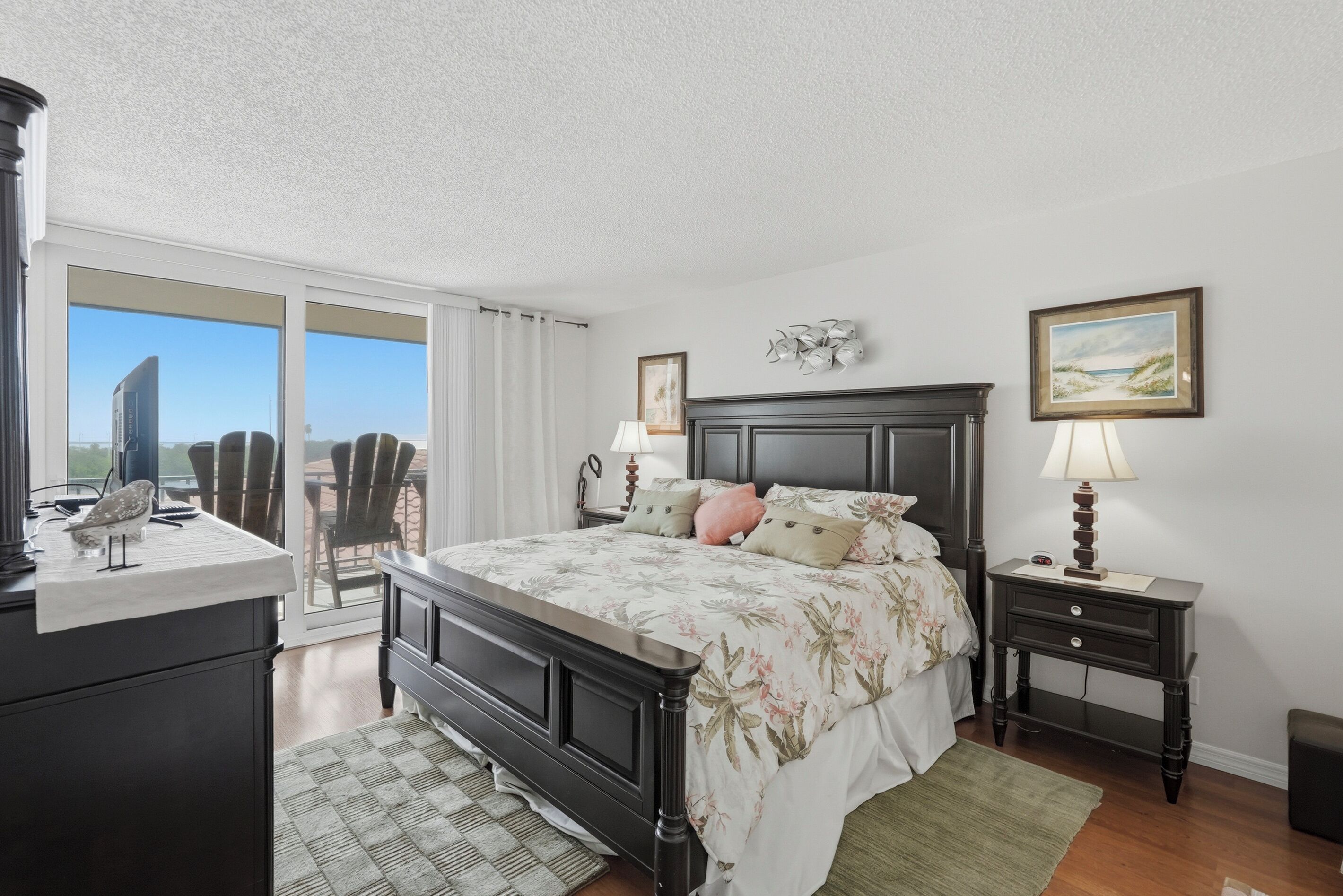 Une chambre à coucher comprenant un lit, des tables de chevet, un bureau, une chaise, une fenêtre avec vue et un tableau accroché au mur.