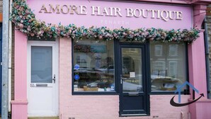 A pink storefront with the sign 'AMORE HAIR BOUTIQUE' and a window displaying various hair products. - Barret Flat, sleeps 4, central location, Penarth (Penarth)