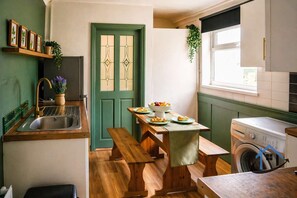 A kitchen with a wooden bench, a sink, a washing machine, and a door with a green frame.