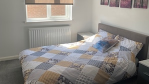 Et soveværelse med seng, et vindue, en radiator og et natbord.