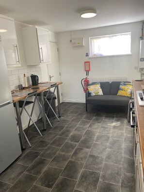 A compact kitchen with a dining area, a grey tiled floor, and a window with a view. - Luxurious 4 Bedroom House in Corby (Corby)