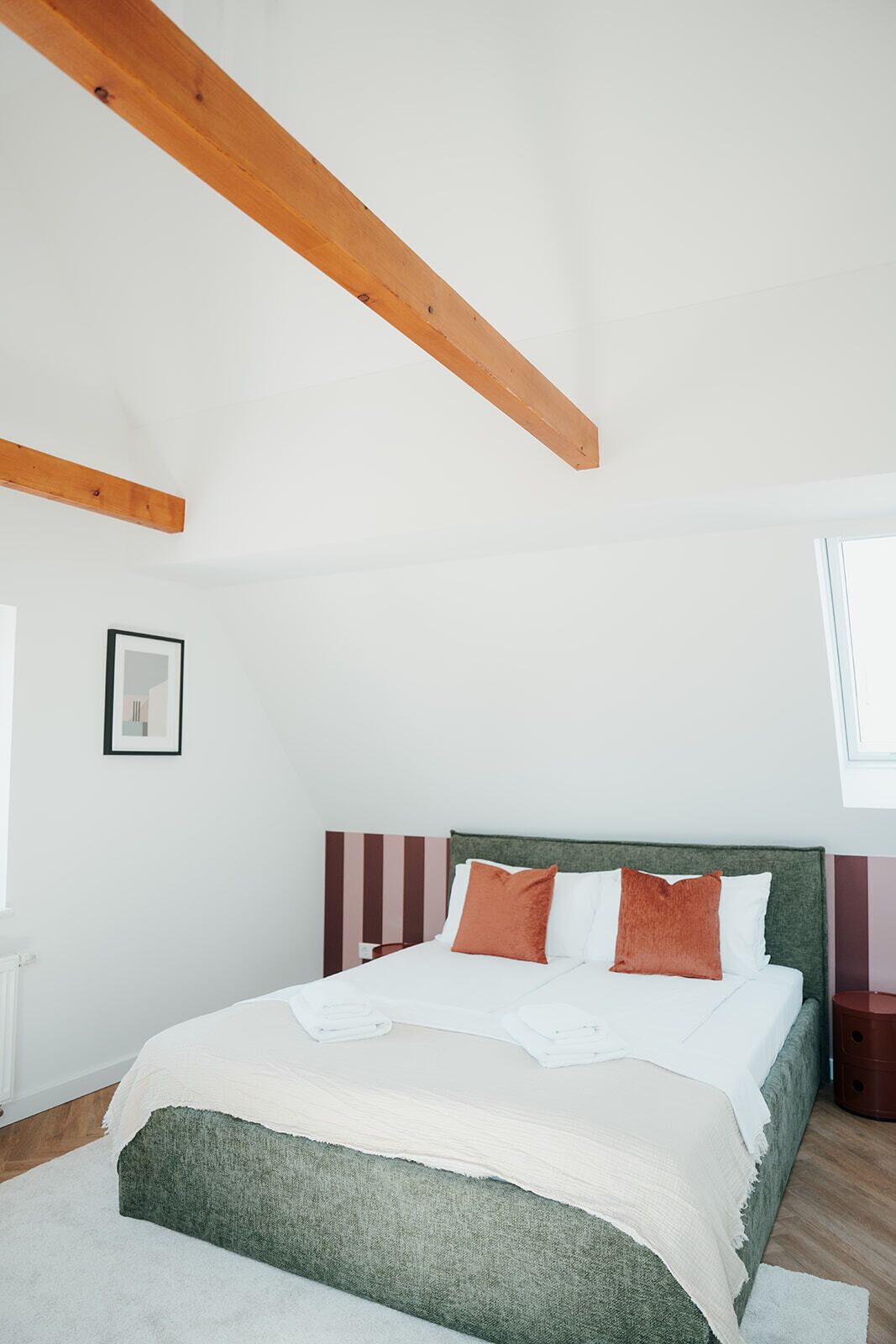 Camera da letto con un letto, una testata, una finestra e travi in legno a vista.