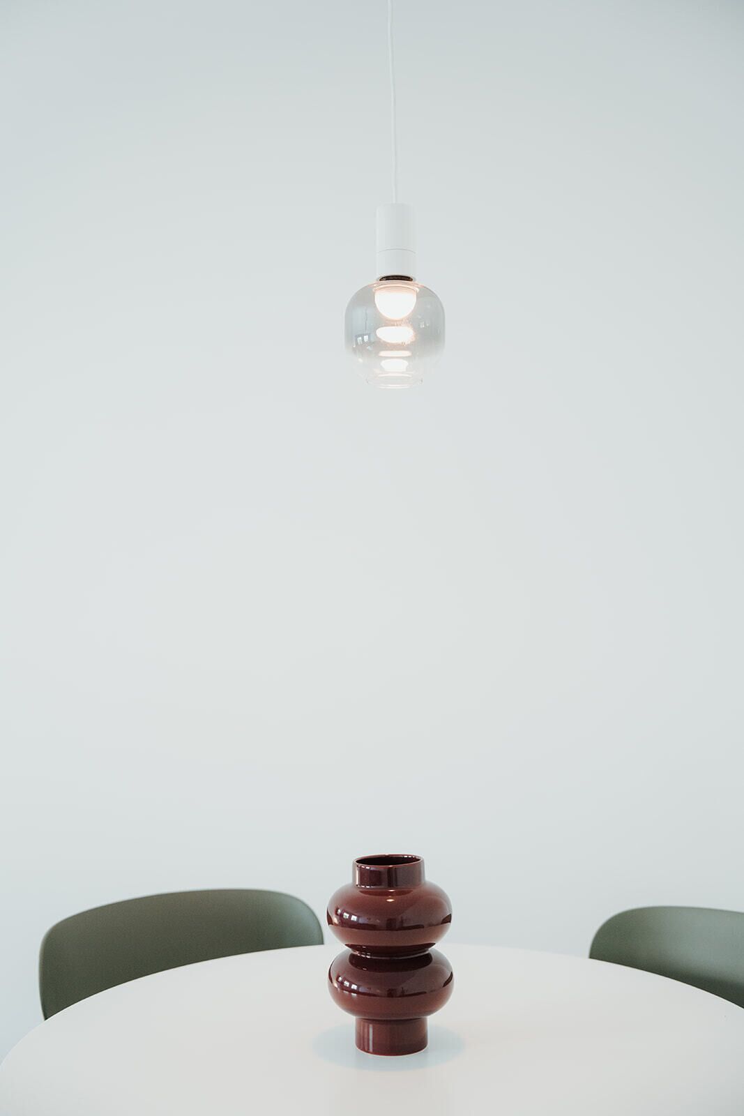 A table with a single decorative vase and a hanging light fixture.