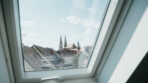 Una ventana de tragaluz con vistas a un paisaje urbano, que incluye edificios y una iglesia con dos torres.