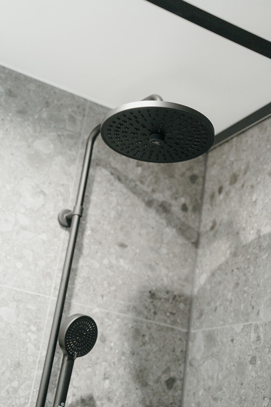 A showerhead with a circular design and a handheld shower attachment.