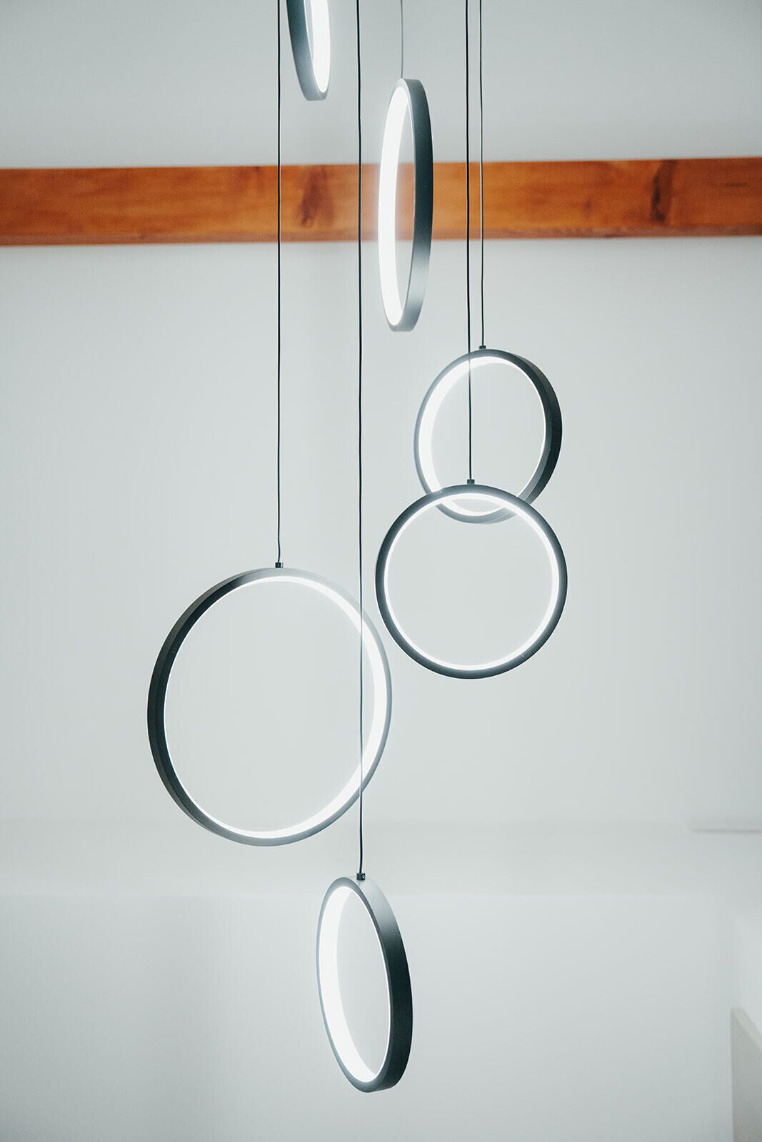 Un interno moderno con travi a cassetto in legno e tre lampade circolari.