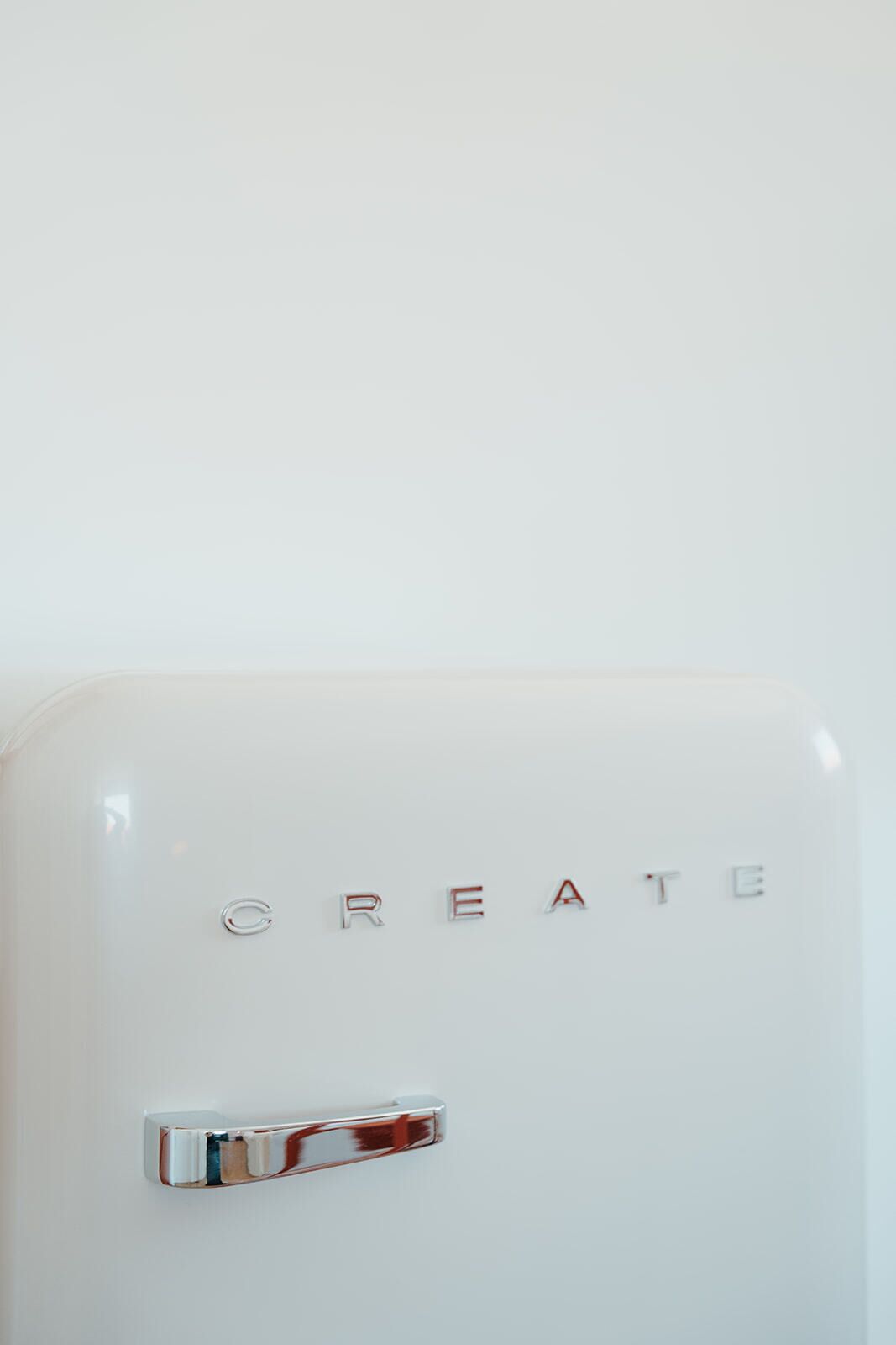 Un objet blanc portant l’inscription « CREATE » en lettres métalliques et doté d’un manche chromé.