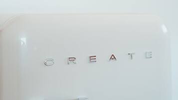 Un objet blanc portant l’inscription « CREATE » en lettres métalliques et doté d’un manche chromé.