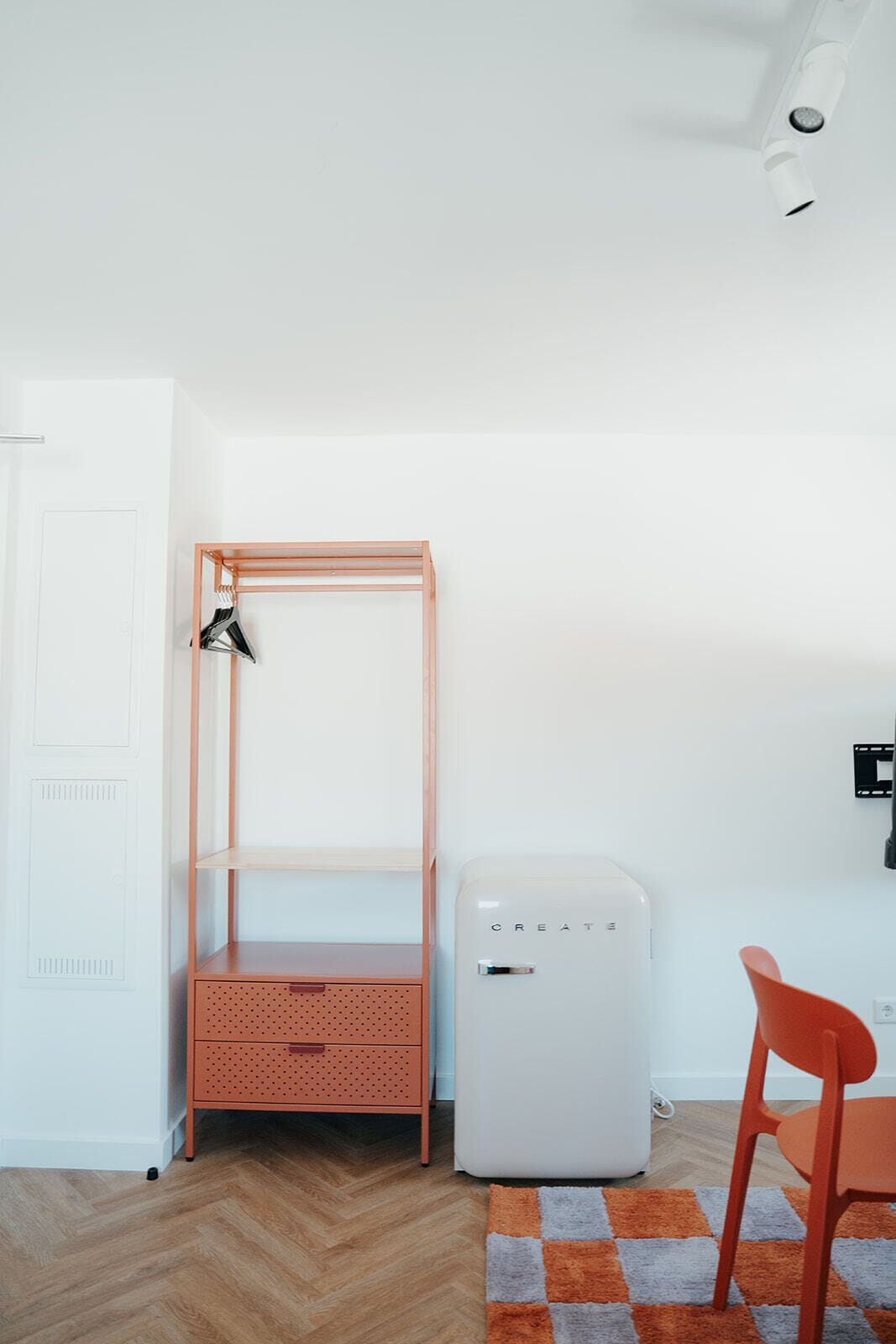 A room with a bunk bed, a small white appliance, a red chair, and a checkered rug.