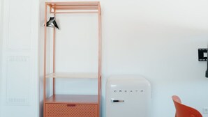 Una habitación con una cama litera, un pequeño electrodoméstico blanco, una silla roja y una alfombra a cuadros.