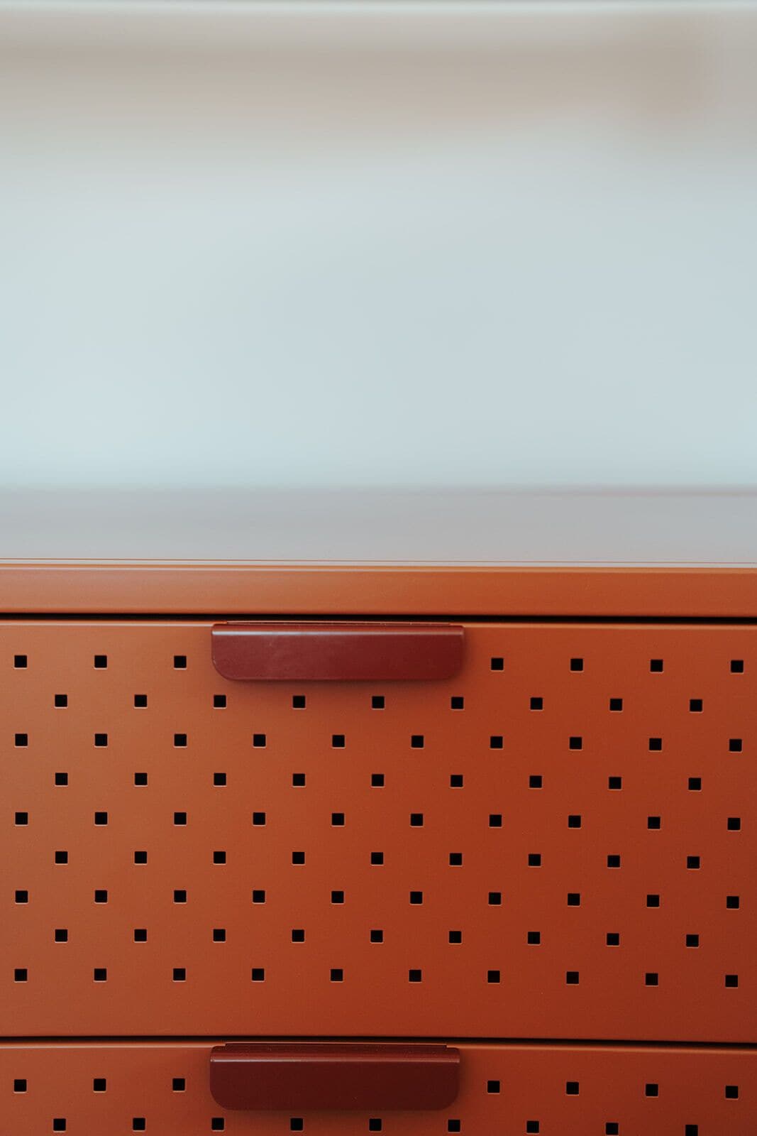 A brown storage unit with a perforated design and two handles.
