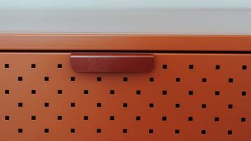 A brown storage unit with a perforated design and two handles.