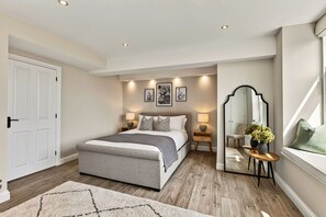 A bedroom with a bed, bedside tables, a mirror, and a window. - Willow's View (Wreay)