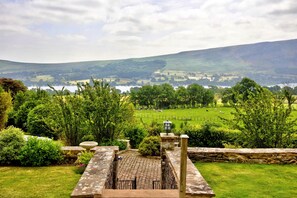 A stone pathway leading to a scenic overlook with a view of a lake and rolling hills in the distance. - Willow's View (Wreay)