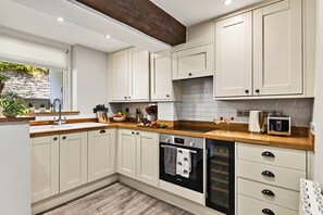 A modern kitchen with white cabinetry, a wooden countertop, a Bosch oven, and a built-in dishwasher. - Willow's View (Wreay)