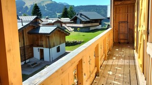 Un balcón de madera con vistas a edificios tradicionales y una montaña al fondo.