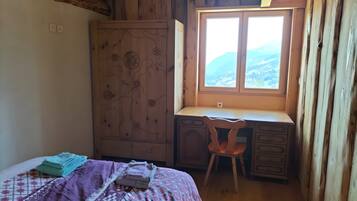 Un dormitorio con cama, escritorio y silla, armario y ventana con vistas.