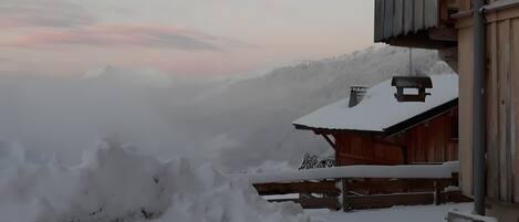 A wooden cabin with a snow-covered roof and a balcony.