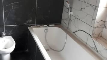 Een badkamer met een bad, een douche en een wastafel.