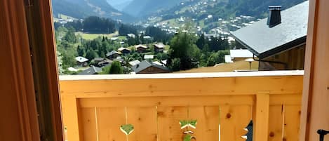 A wooden balcony with a view of a mountainous landscape.