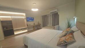 Una habitación de hotel moderna con cama, escritorio, armario y aire acondicionado.