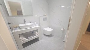 Un baño con lavamanos, espejo y retrete blancos.