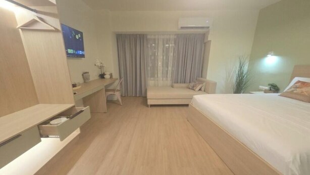 Una habitación de hotel con cama, escritorio, silla y televisión.