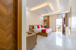 A modern hotel room with a bed, bedside table, and a small desk with a chair. - Castle Prime (New Delhi)