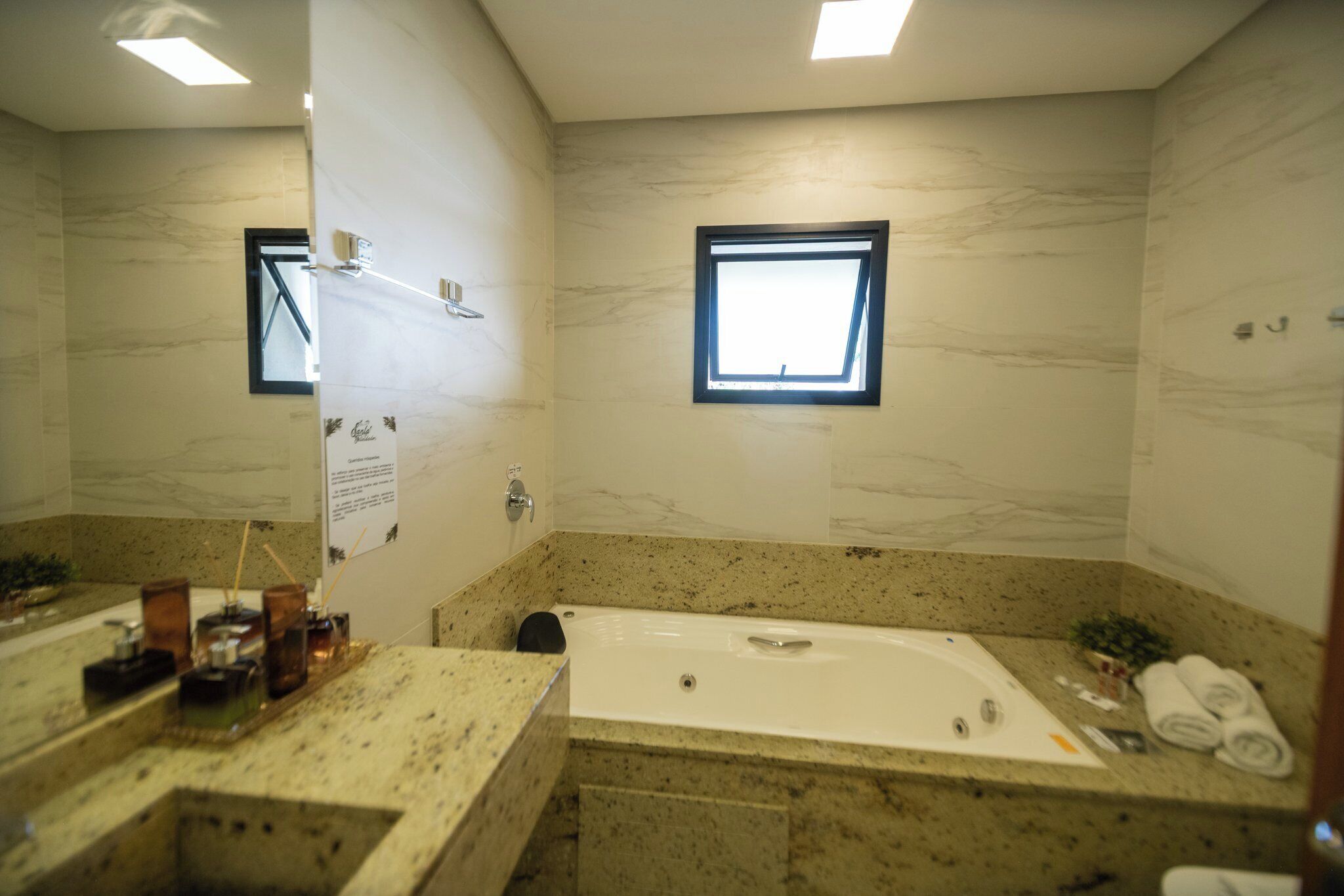 Ein Badezimmer mit einer großen Badewanne, einem Fenster und einem Spiegel.